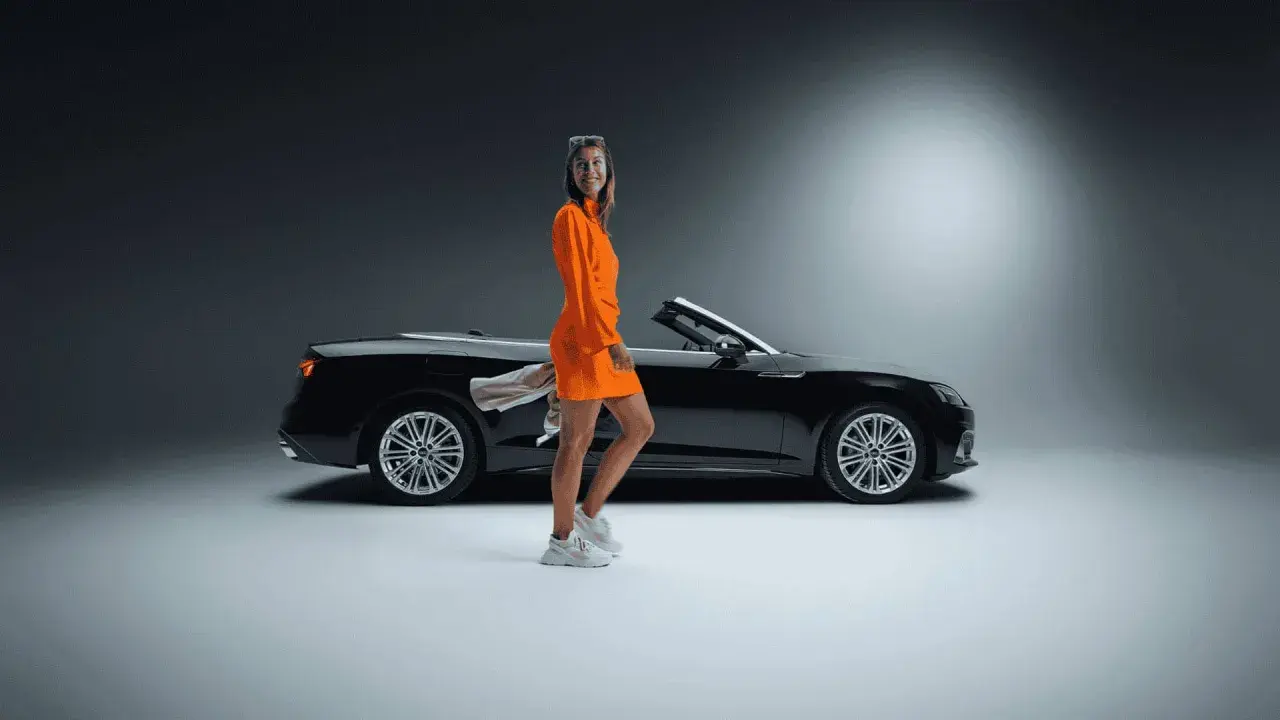 Frau in orangefarbenem Kleid neben schwarzem Cabrio. Ein toller Sixt Aktie Rabatt für Ihre nächste Fahrt!