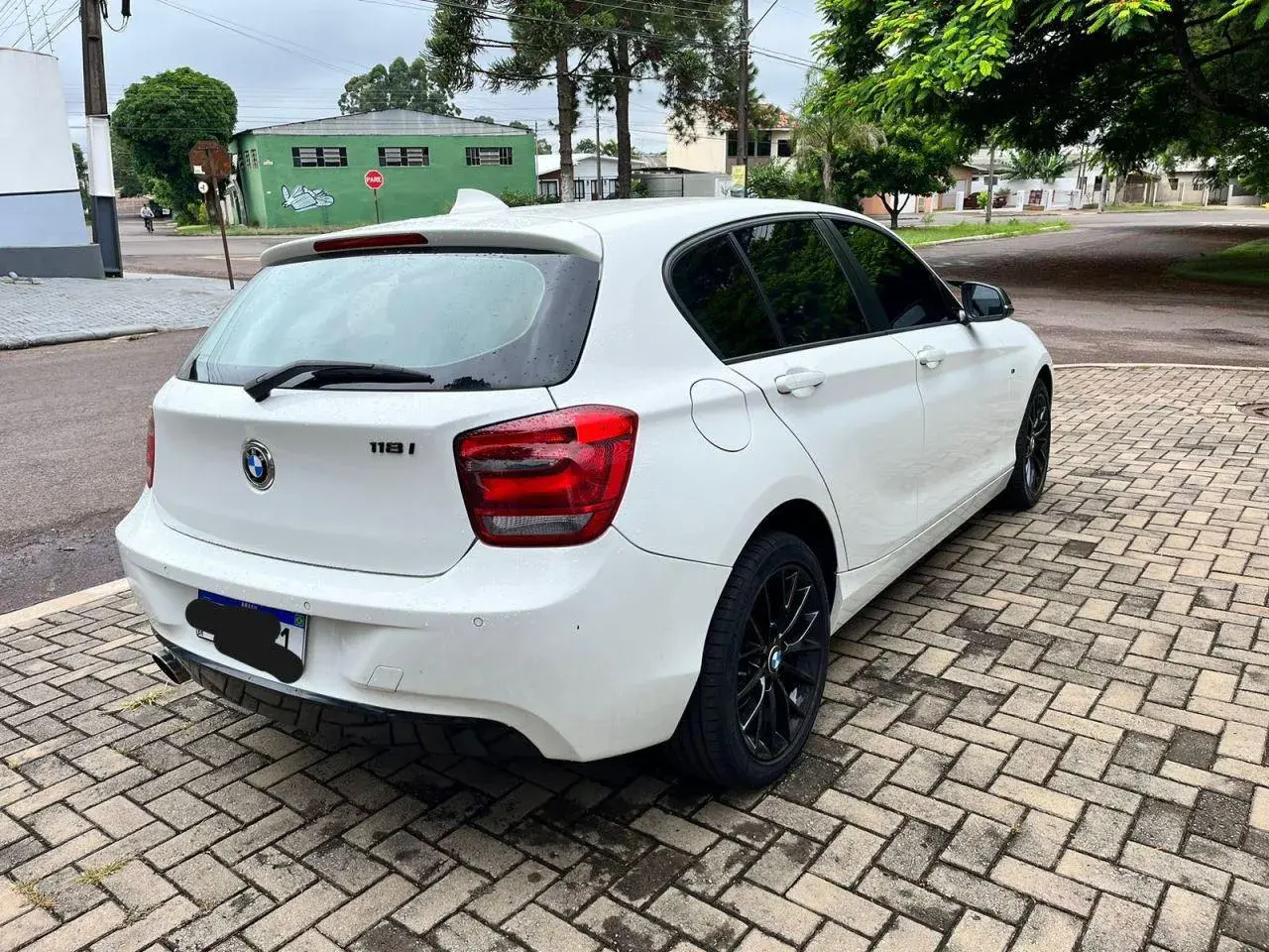 Vit vit BMW 118i står parkerad på en stenlagd uppfart. Kanske ett problem med bilen?