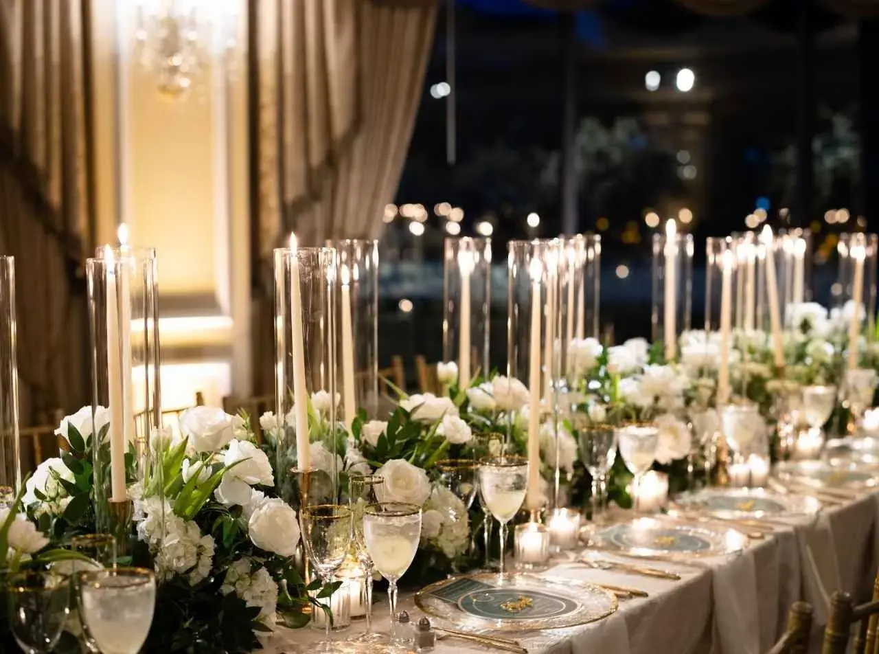 Elegancka dekoracja stołu weselnego z białymi kwiatami i świecami. Sprawdź, jaka jest florystka na wesele cena za takie cuda.