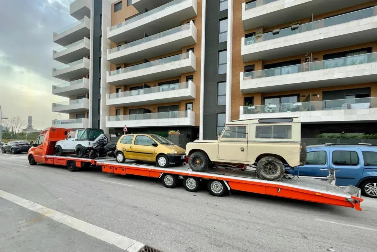 Laweta z autami: żółty Twingo, biały terenowy i beżowy Land Rover. B+E DMC.
