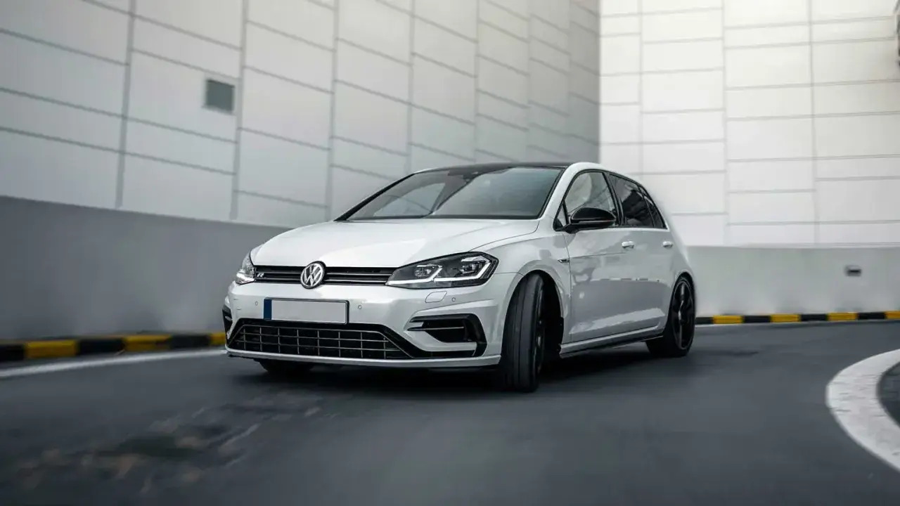 Vit Volkswagen Golf R, en bil som kan drabbas av 1.4 TSI-problem, kör på en asfalterad väg.
