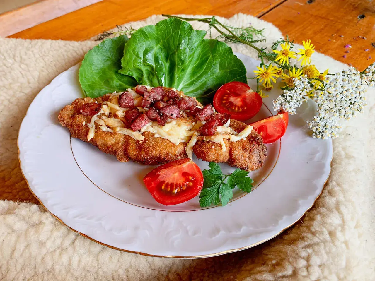 Schab po góralsku, panierowany kotlet z serem i boczkiem, podany z pomidorami i sałatą.