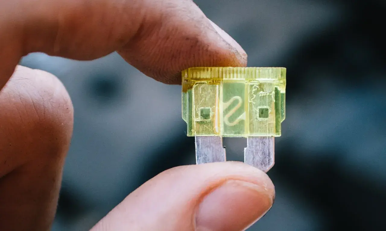 Dedo sostiene un fusible luz de freno amarillo de 20 amperios, listo para reemplazar uno quemado.