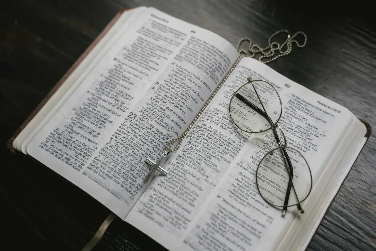Otwarta Biblia, krzyż na łańcuszku i okulary. Może to symbolizować św. Brygidę, jej modlitwę i 12-letnie objawienia.