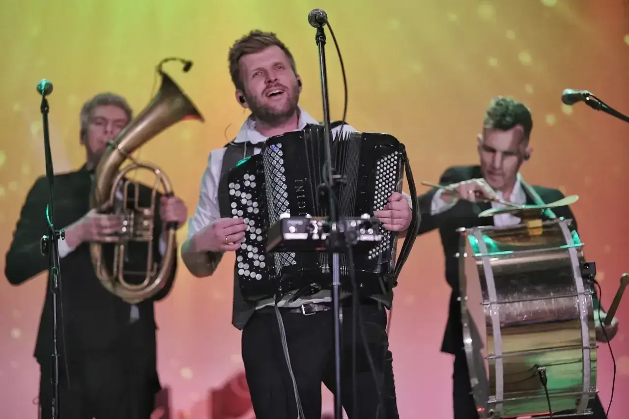 Bum bum orkestar w akcji: akordeonista, tubista i perkusista tworzą energetyczną muzykę na scenie.
