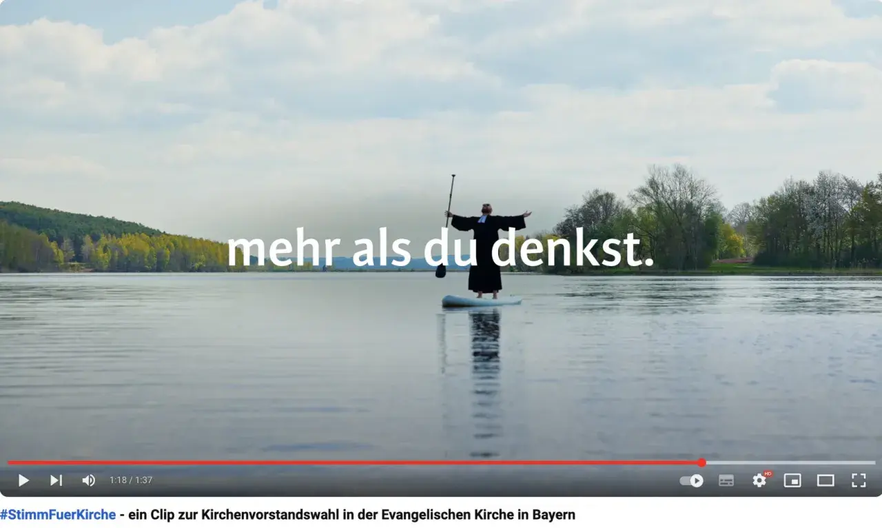 Ein Geistlicher steht auf einem SUP-Board auf einem See. Der Arbeitgeber Kirche bietet mehr als man denkt.