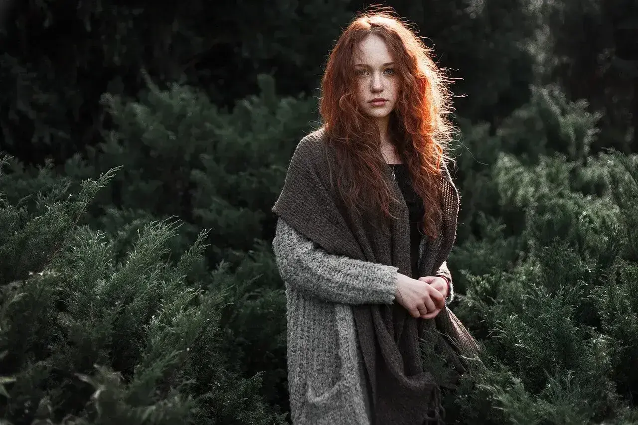 Rudowłosa dziewczyna w jesiennym otoczeniu, otulona ciepłym szalem. To piękna fotografia kreacyjna.