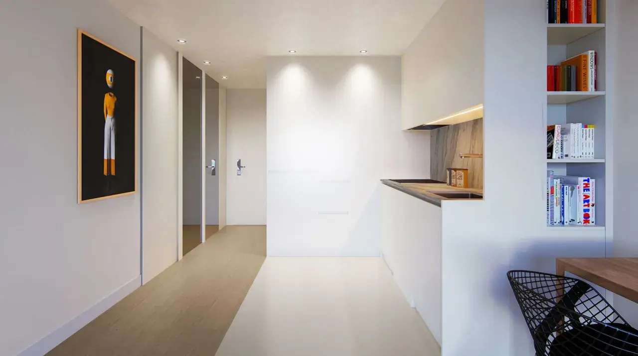 Pasillo moderno con arte abstracto y cocina minimalista, creando un ambiente de flujo luminoso.