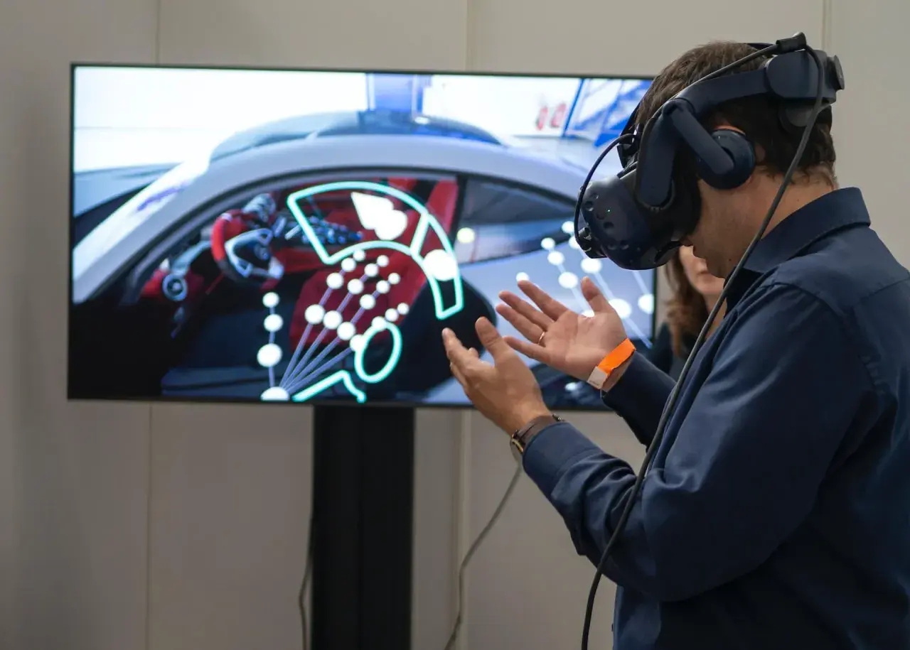 Un homme porte un casque de réalité augmentée, explorant un tableau de bord de voiture virtuel.