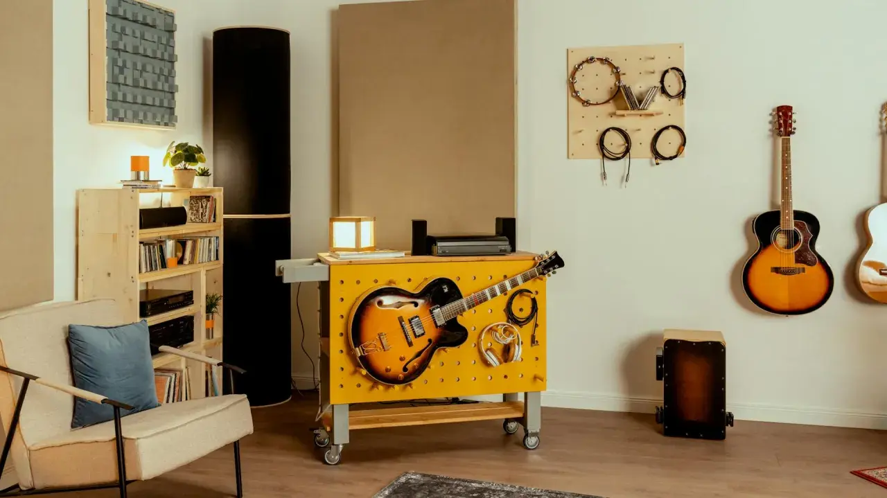 Kreative hobbykeller ideen: Gitarren, Kopfhörer und Kabel sind ordentlich an einer gelben Werkbank mit Lochwand befestigt. Akustikpaneele und weitere Instrumente schaffen eine musikalische Atmosphäre.