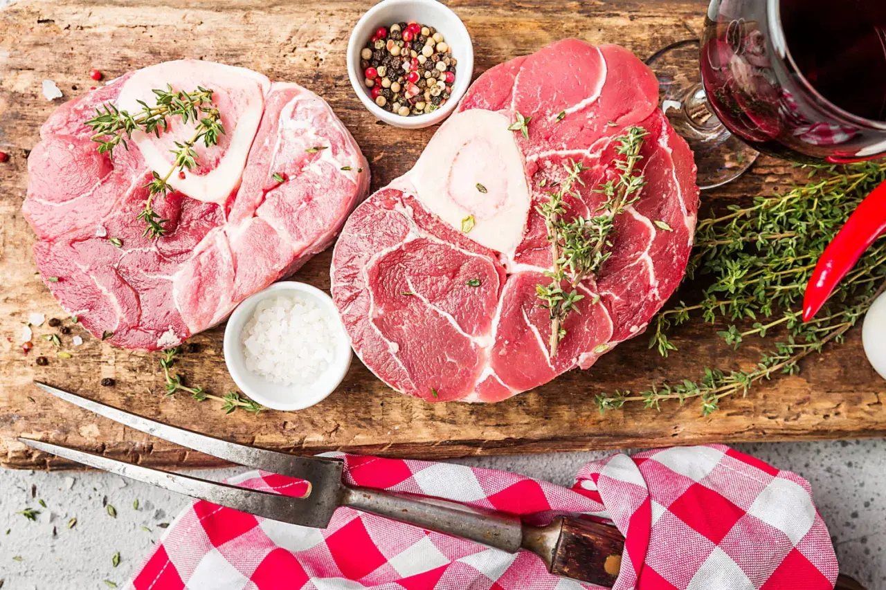 Deux belles pièces de viande blanche, du sel, des poivres, du thym et un piment rouge sur une planche en bois.