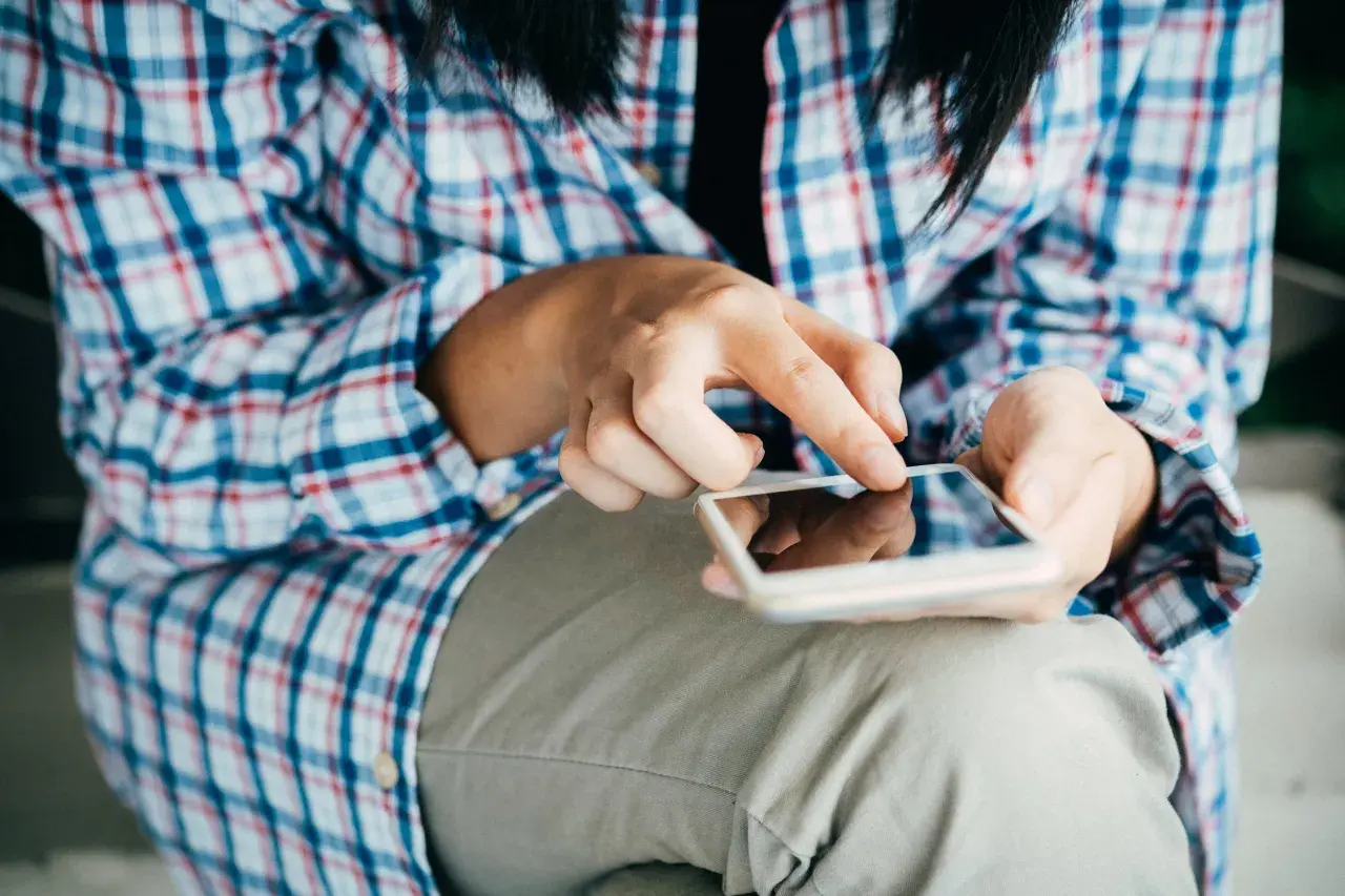 Mani che scorrono su uno smartphone, forse per esplorare il sexting perché si fa, un modo per connettersi.