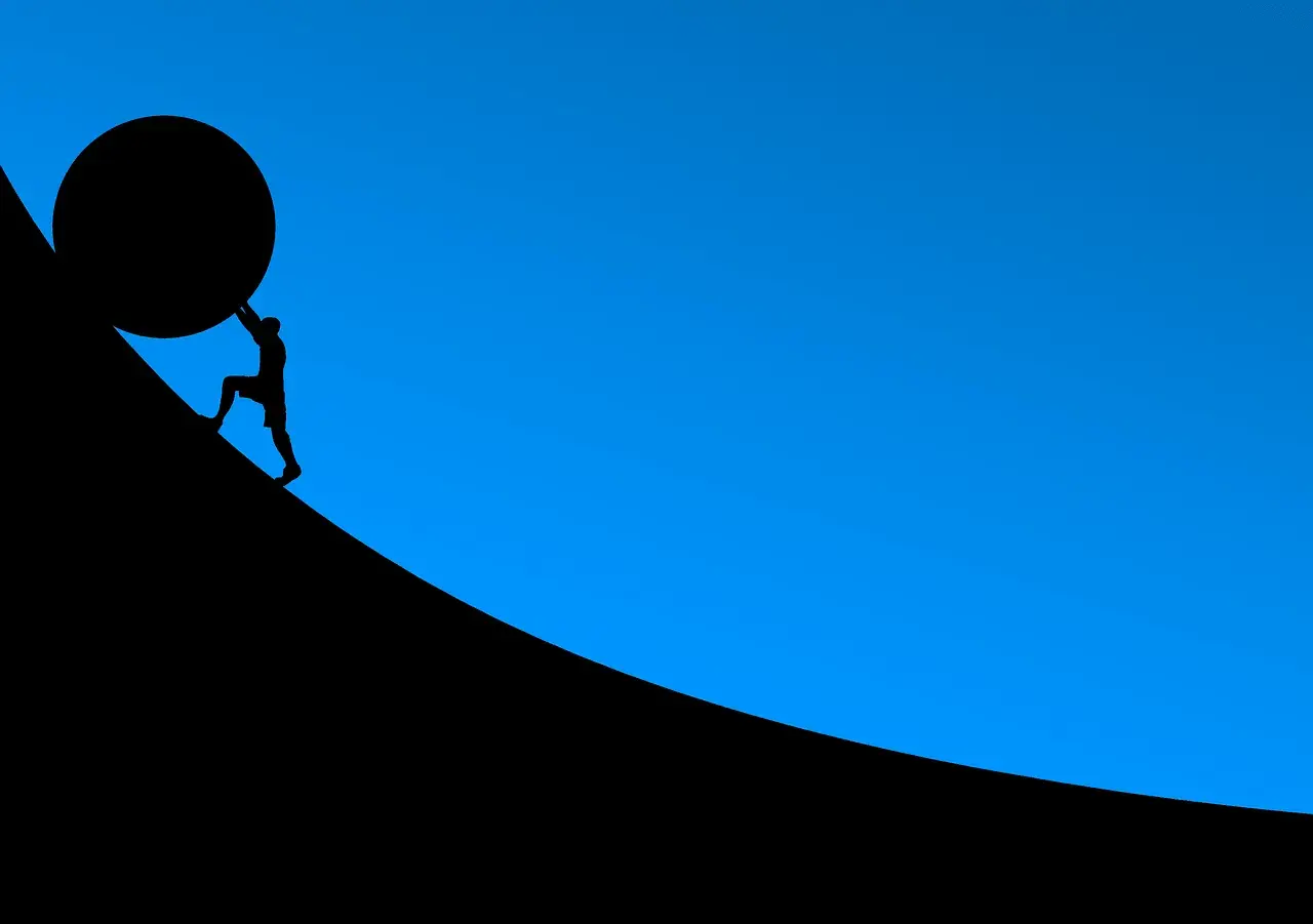 Silhouette d'un homme poussant une énorme sphère sur une pente. L'effort pour un prêt immobilier 30 ans.