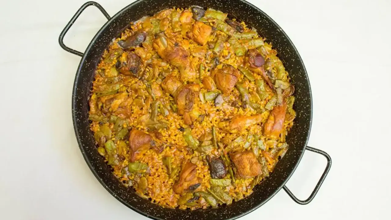 Paella mixta recién hecha, con pollo, judías verdes y arroz dorado. Un delicioso paella rezept para compartir.