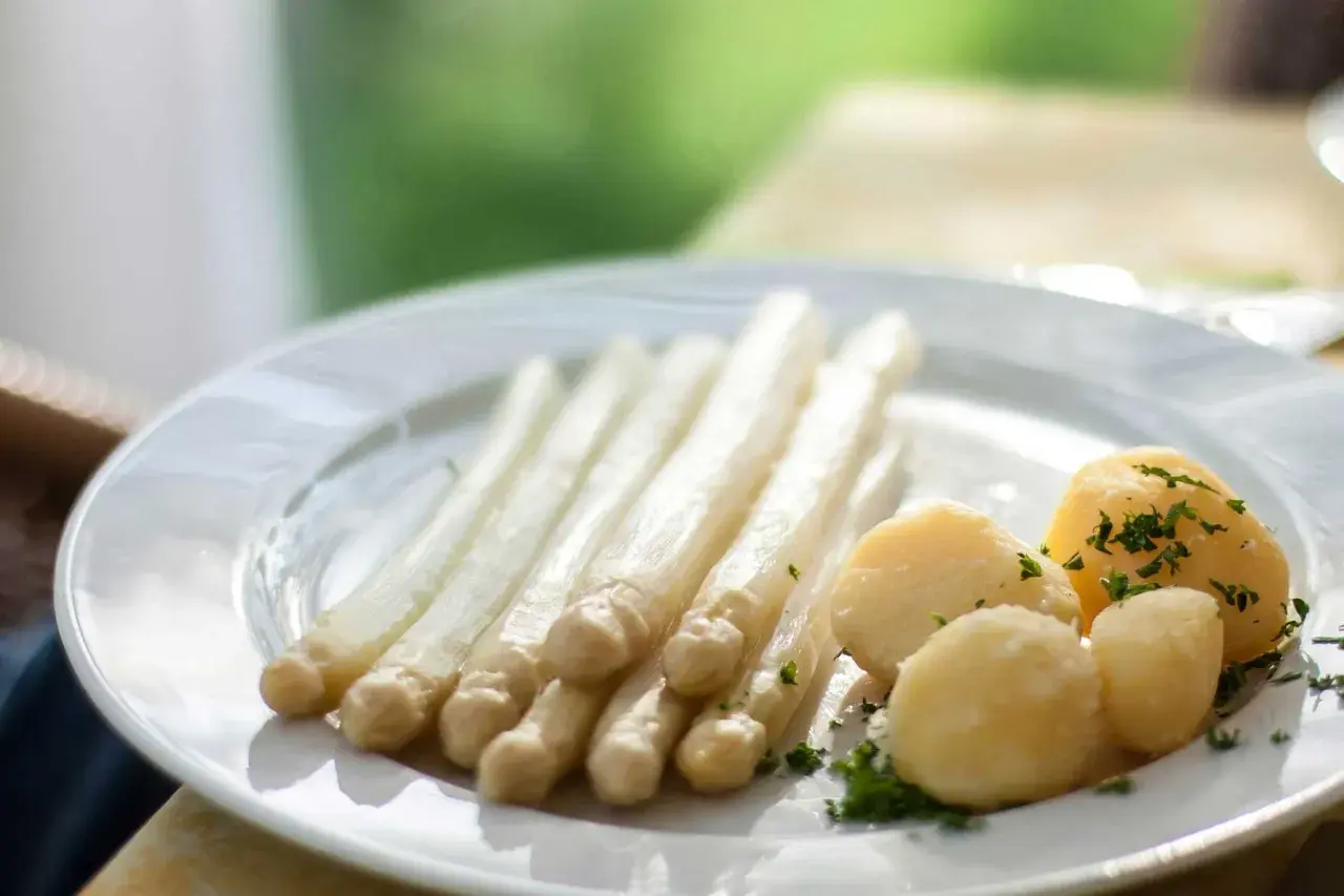 Ein Teller mit weißem Spargel und Salzkartoffeln, garniert mit Petersilie. Perfekt für einfache Spargel Rezepte.