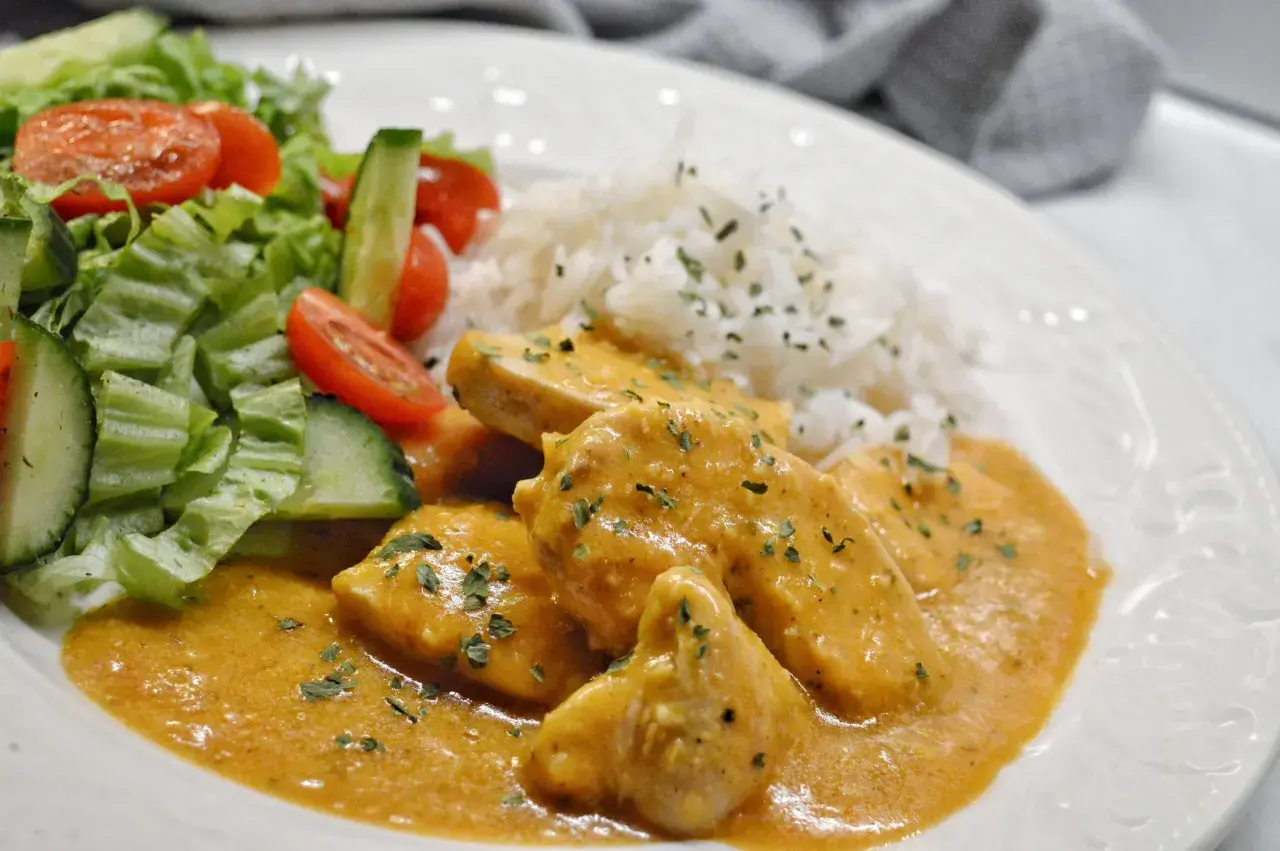 En krämig kyckling korma med ris och en fräsch sallad på tomat och gurka.