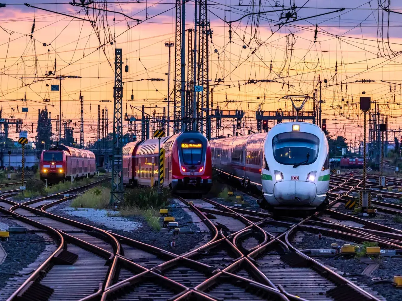 Mehrere Züge auf Bahngleisen bei Sonnenuntergang. Das Deutschlandticket gilt einen Monat lang.