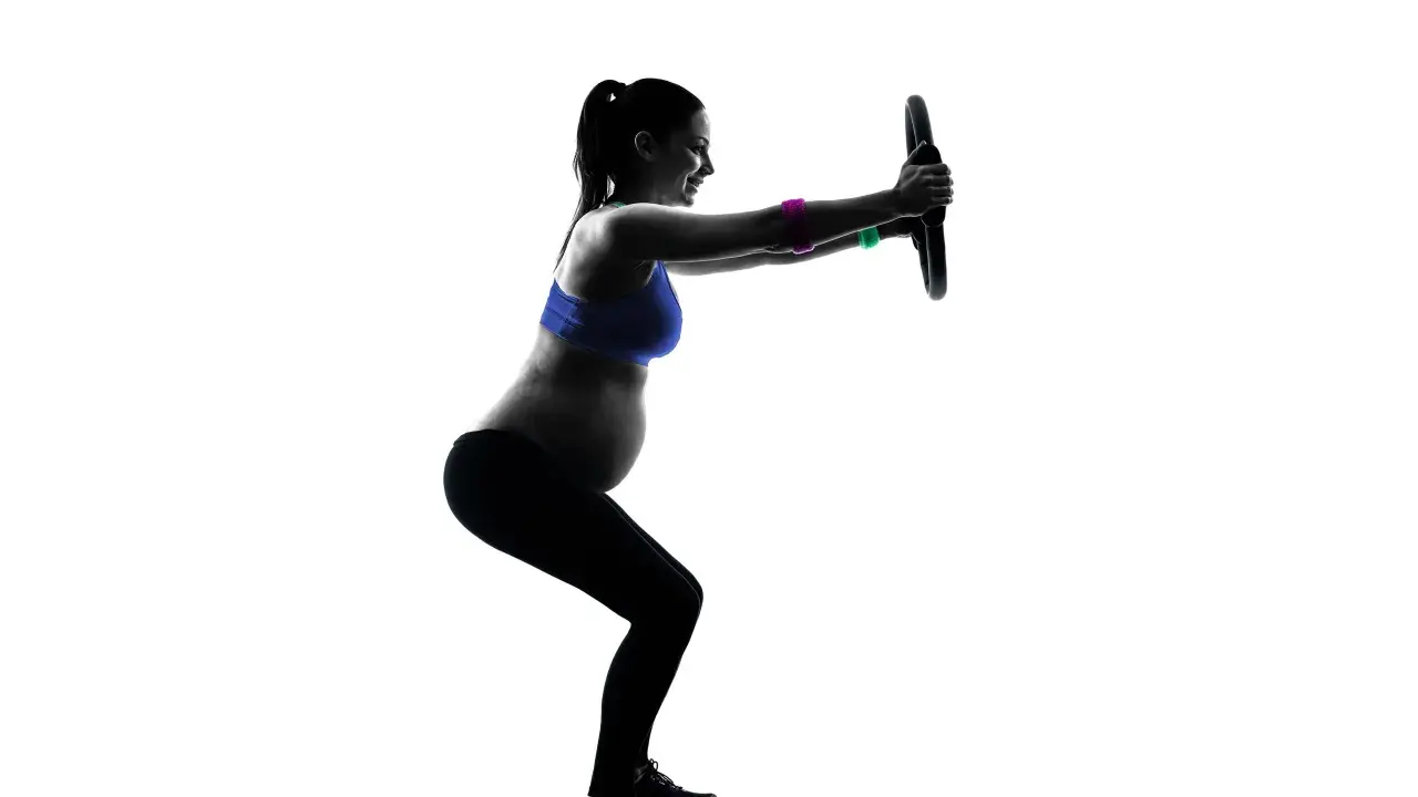 Gravid kvinna tränar pilates med en ring.