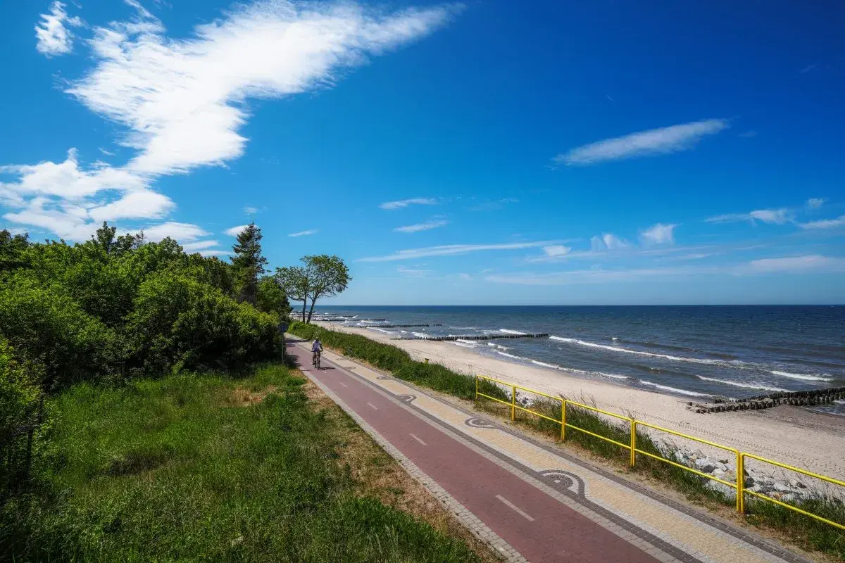Ścieżka rowerowa nad Bałtykiem, plaża i morze w słoneczny dzień.