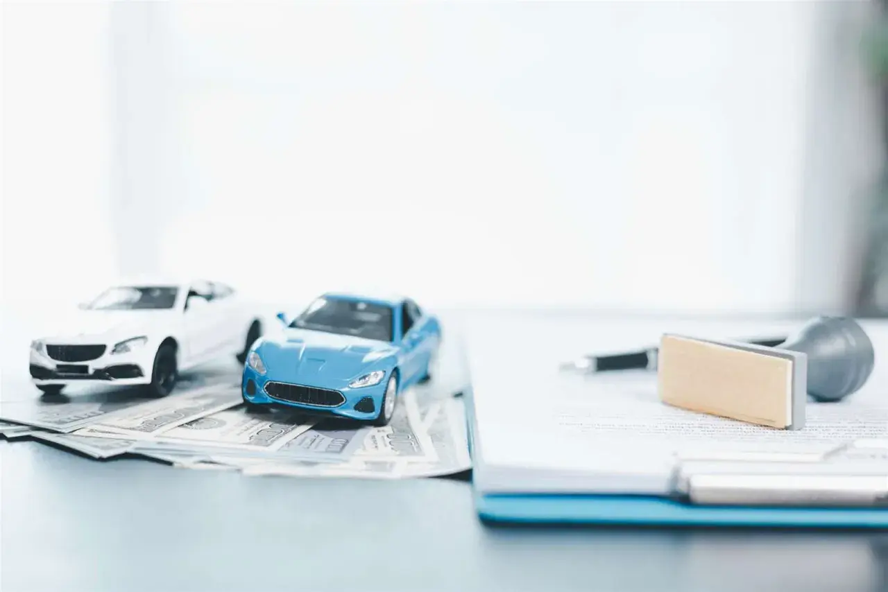 Modellini di auto su banconote, con documenti e timbro. Pensando a come disdire assicurazione auto prima della scadenza.
