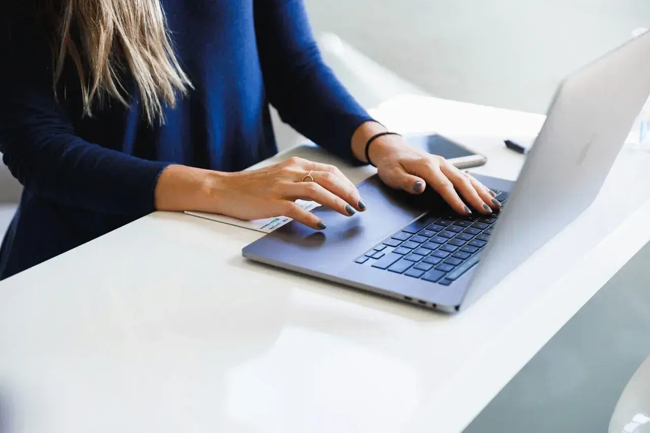 Mani di donna su tastiera laptop, analizzando il costo aziendale.