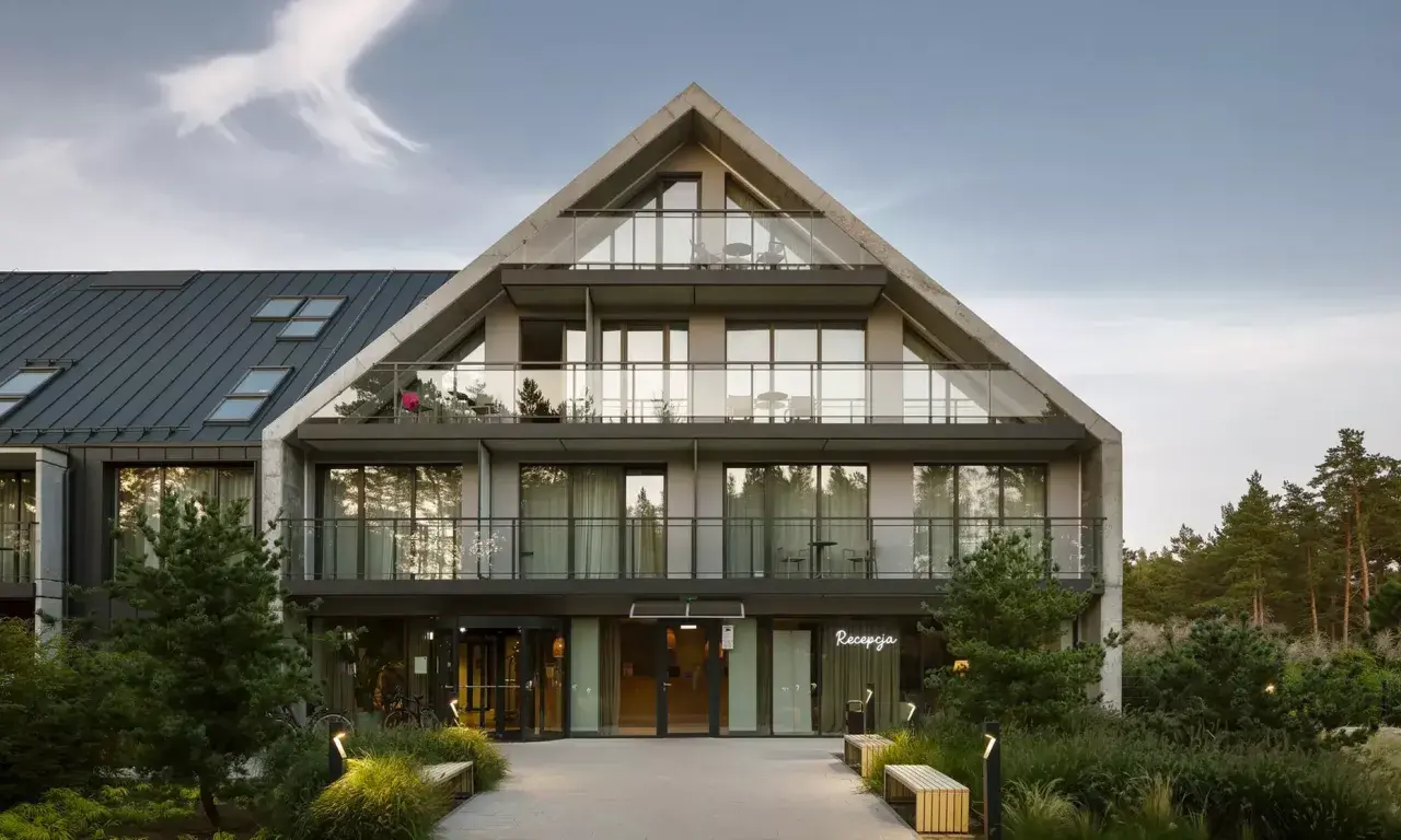 Nowoczesny budynek hotelowy Saltic Resort & Spa Łeba z betonową fasadą i przeszklonymi balkonami.