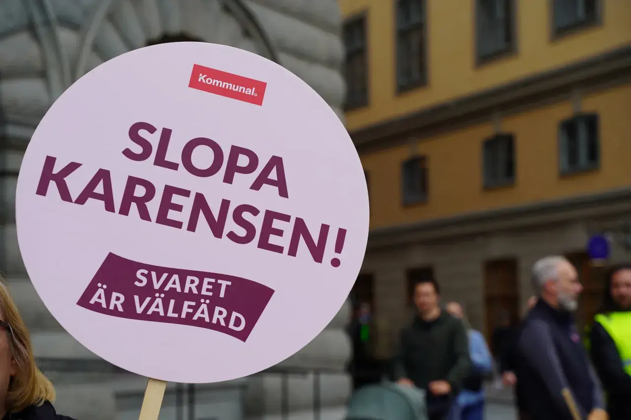 En demonstration mot karensdag regler. Skylten lyder "Slopa karensen! Svaret är välfärd" och bär Kommunals logotyp.