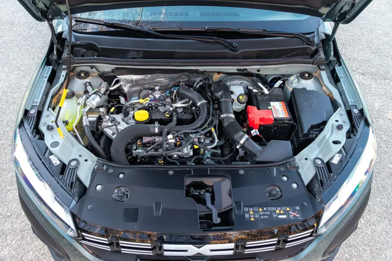 Vista del motor de un Dacia Sandero Stepway. Se aprecian componentes como la batería, el depósito de refrigerante y el sistema de admisión de aire.