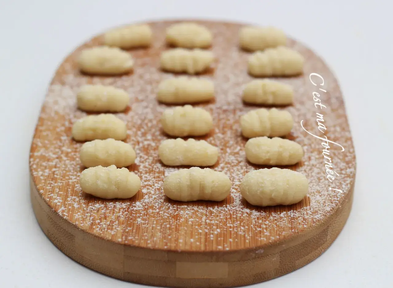 Gnocchis faits maison, une délicieuse pâte italienne à base de pomme de terre, saupoudrés de sucre glace sur une planche en bois.