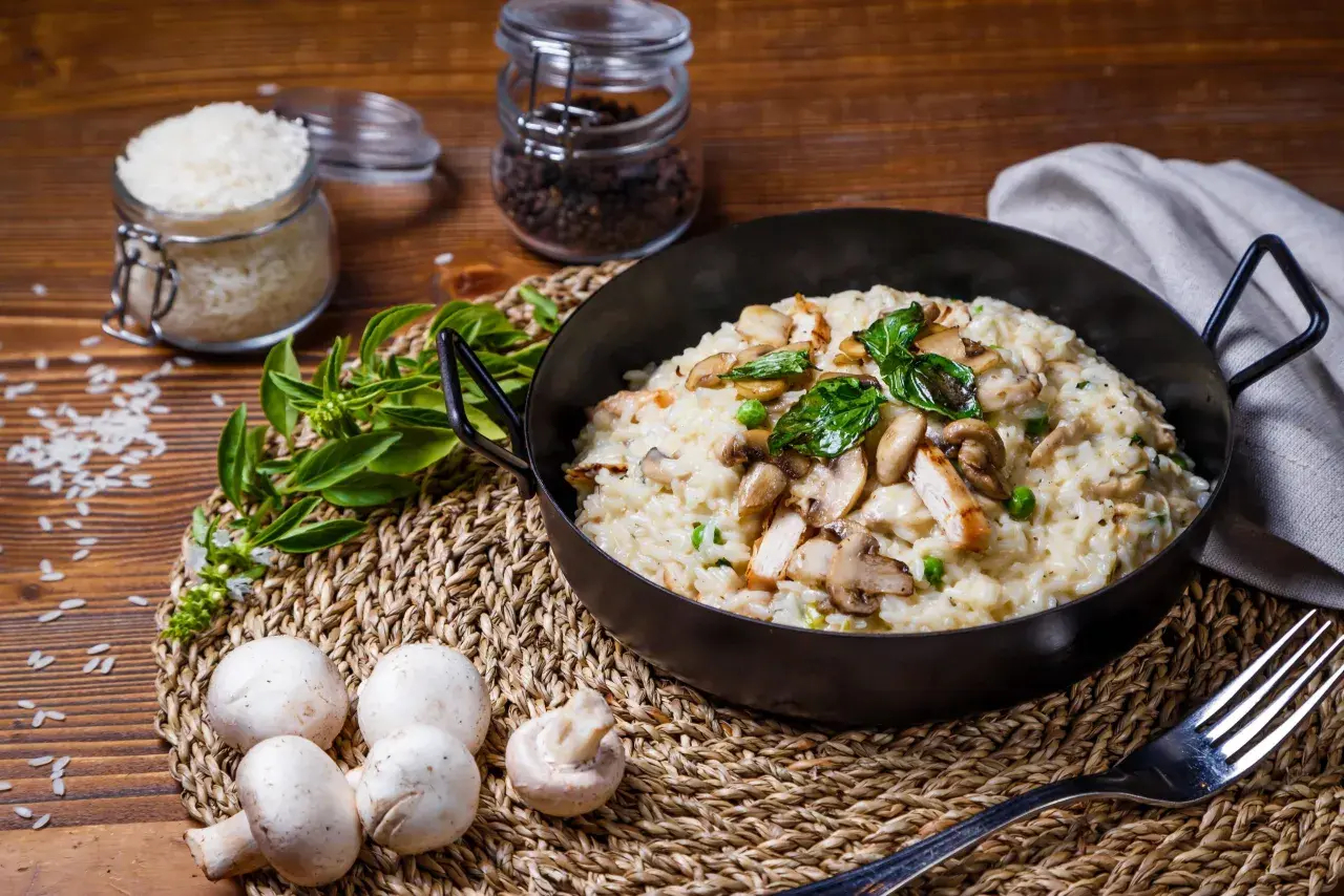 Un crémeux risotto poulet champignon, garni de basilic frais, prêt à être dégusté.