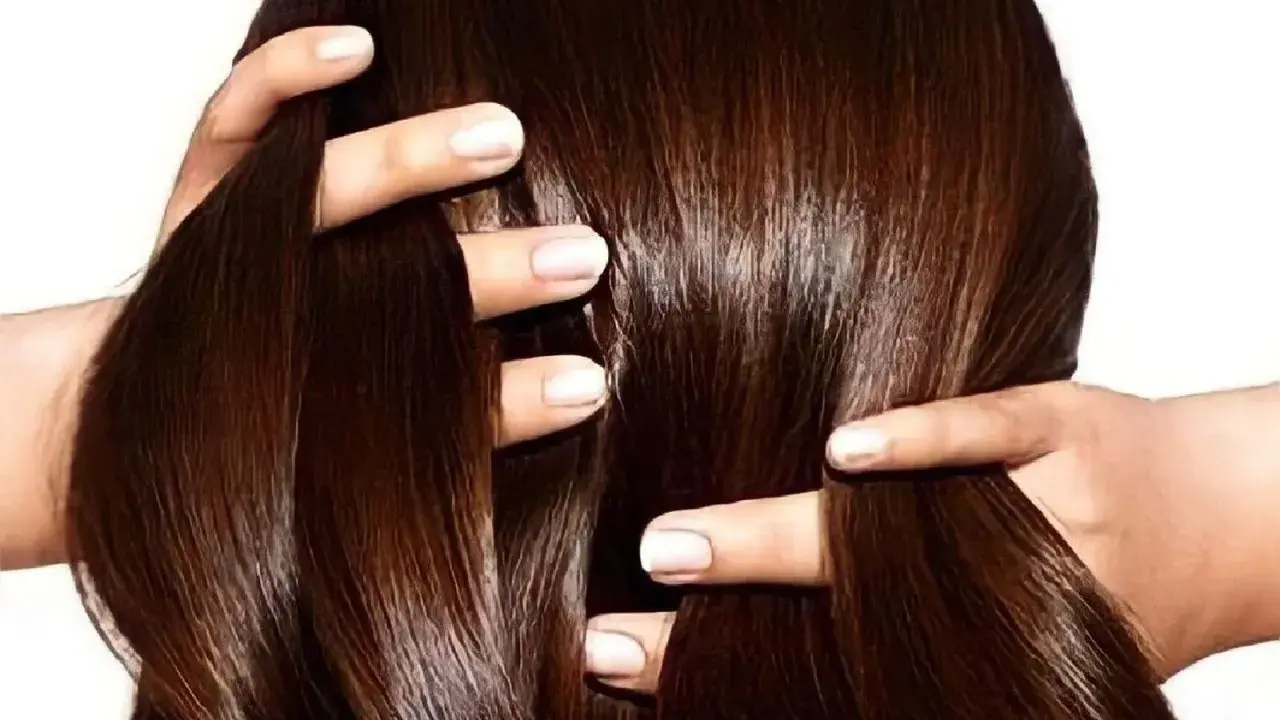 Manos peinando un cabello largo y sedoso de color chocolate.
