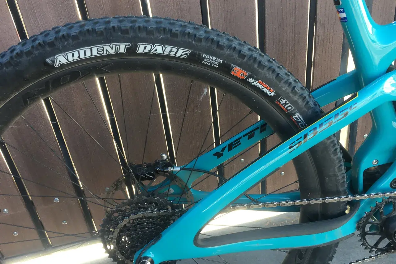 Close-up of a turquoise Yeti mountain bike rear wheel, featuring a Maxxis Ardent Race tire.