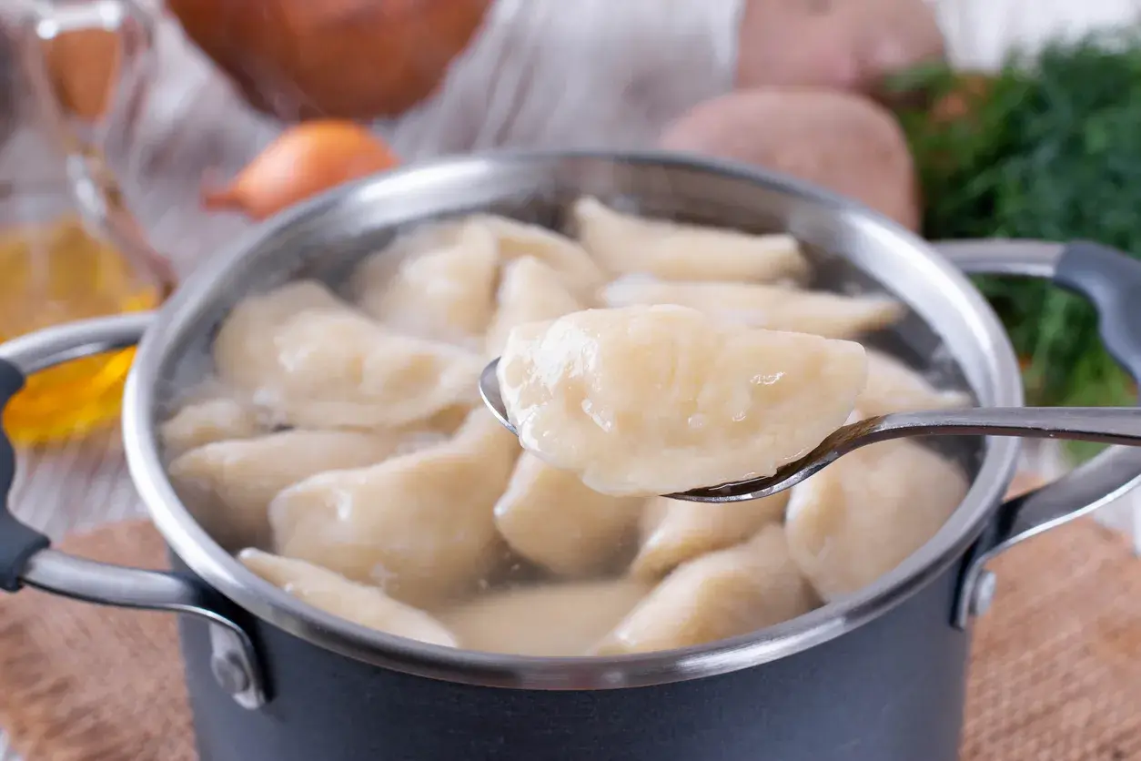 Gotowane pierogi w garnku, jeden na łyżce. Czy płukać pierogi po ugotowaniu? Zależy od przepisu!