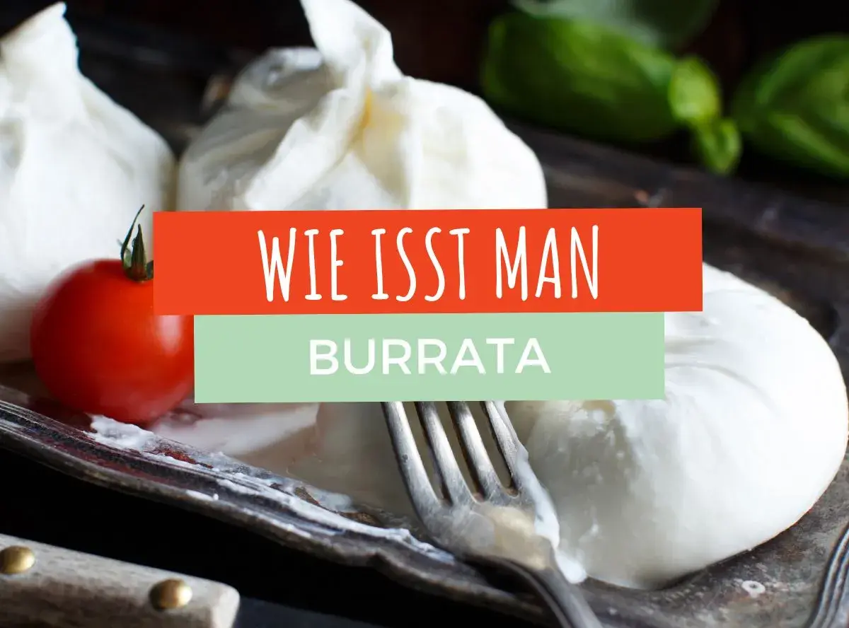 Frische Burrata mit Tomate und Basilikum auf einem Teller. Ein Gabel liegt daneben. Der Text "Wie isst man Burrata" ist eingeblendet.