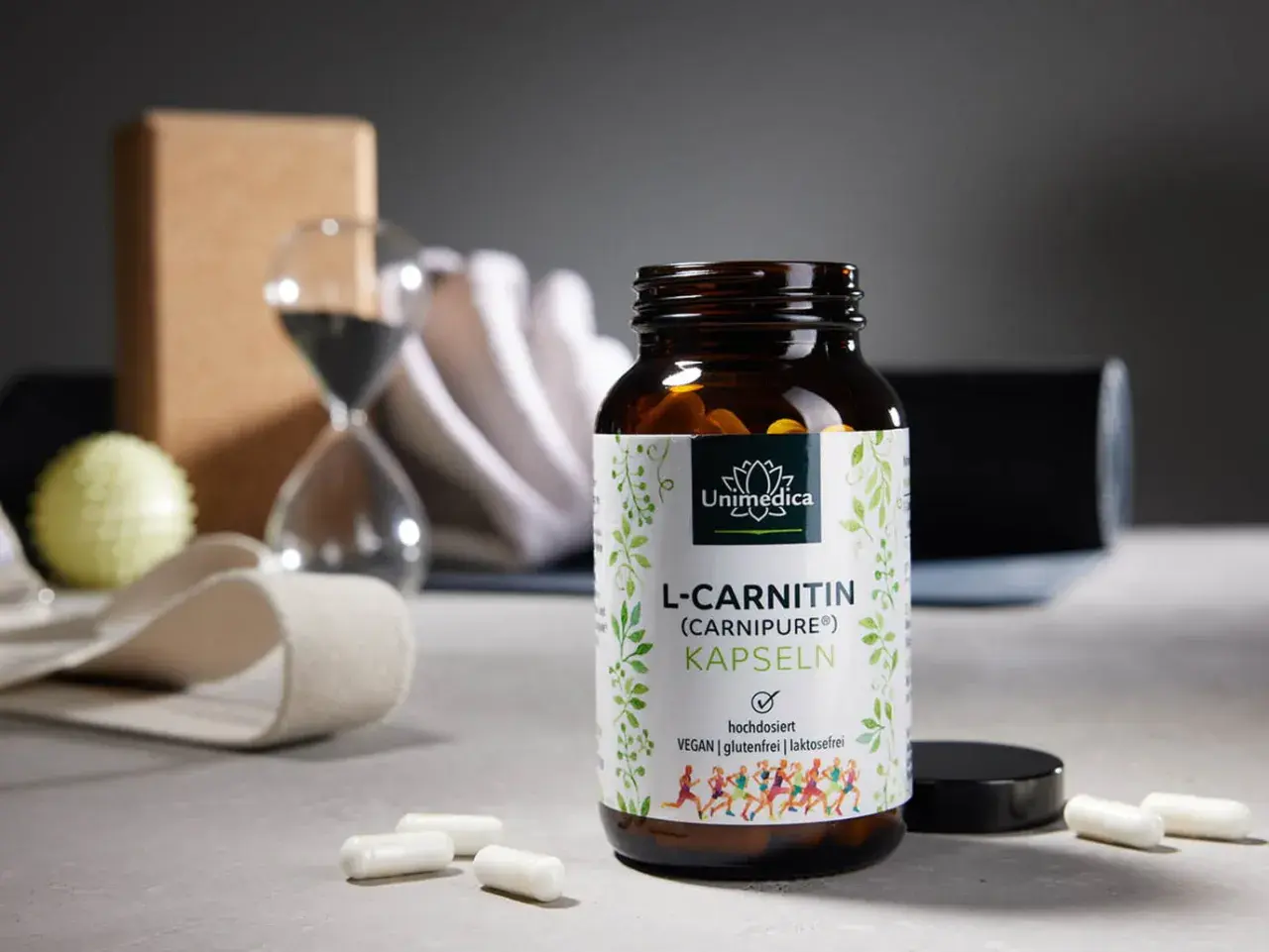 Flasche L-Carnitin Kapseln neben Yoga-Zubehör. Die richtige L-Carnitin Dosierung für dein Training.