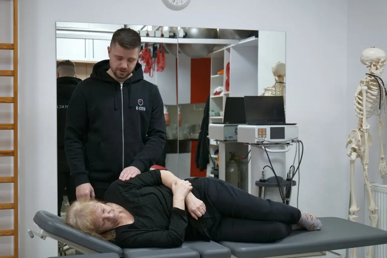 Fizjoterapeuta bada pacjentkę leżącą na kozetce.