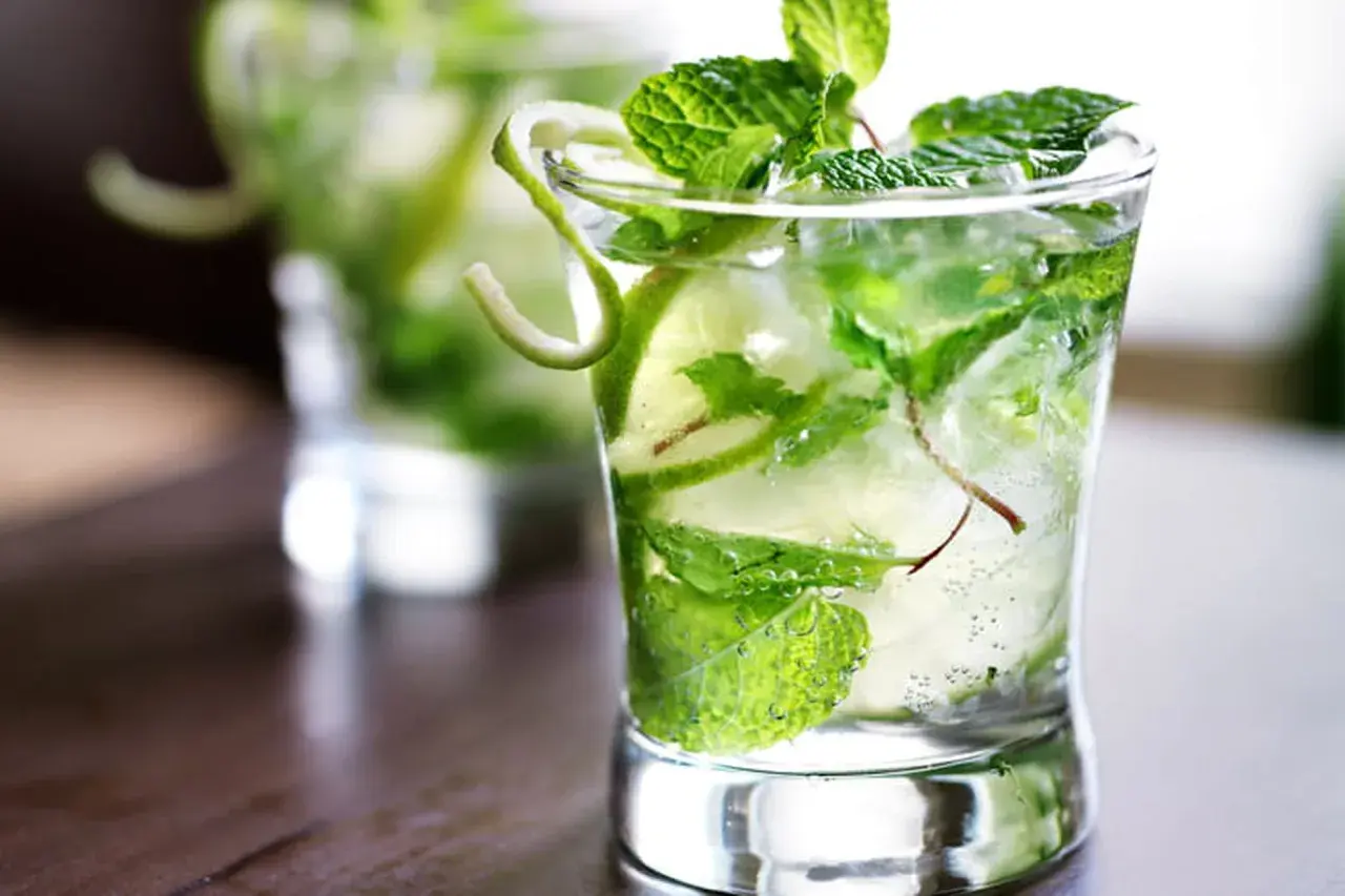 Un verre de virgin mojito rafraîchissant, rempli de glaçons, menthe fraîche et rondelles de citron vert.