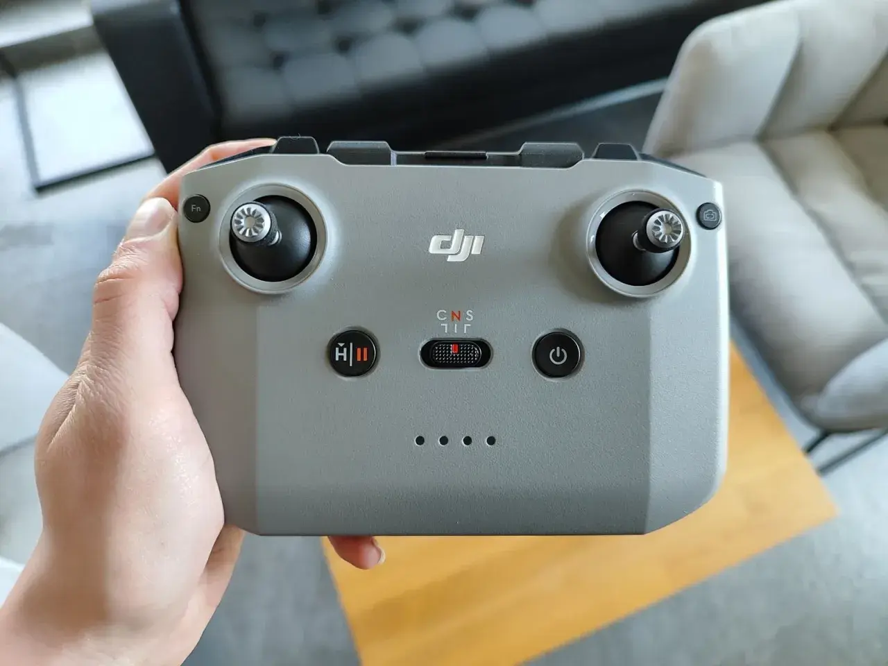 Dłoń trzyma szary kontroler DJI, gotowy do sterowania dronem.
