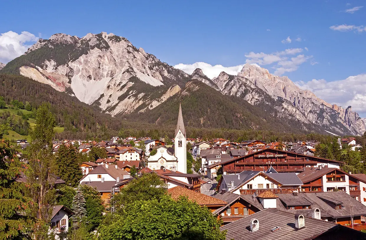 Charming Italy mountain towns nestled at the foot of majestic peaks. A church steeple rises above the rooftops.