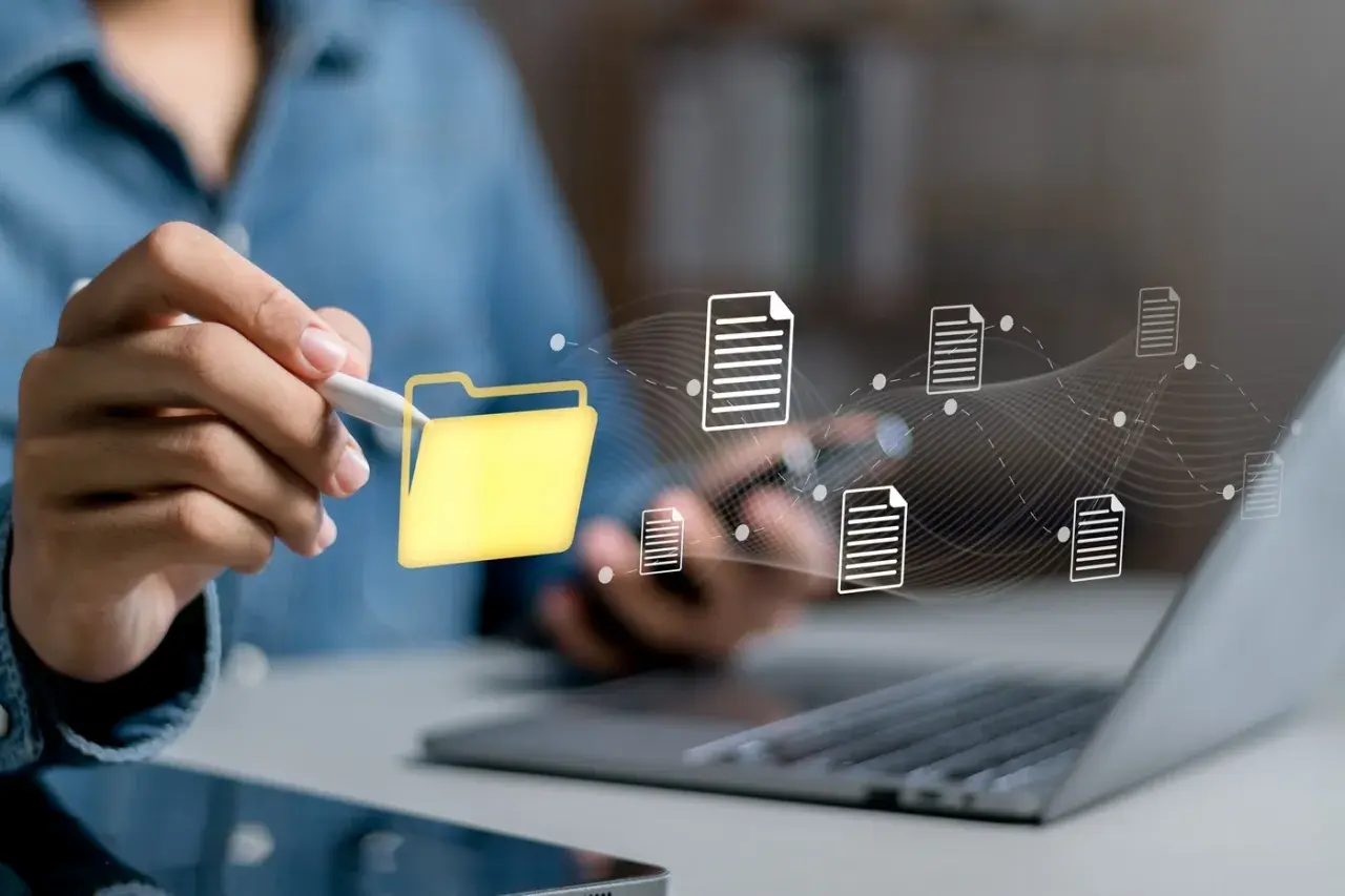 Main d'une personne utilisant un stylet pour interagir avec une icône de dossier jaune, symbolisant la digitalisation des processus et le flux de documents numériques.
