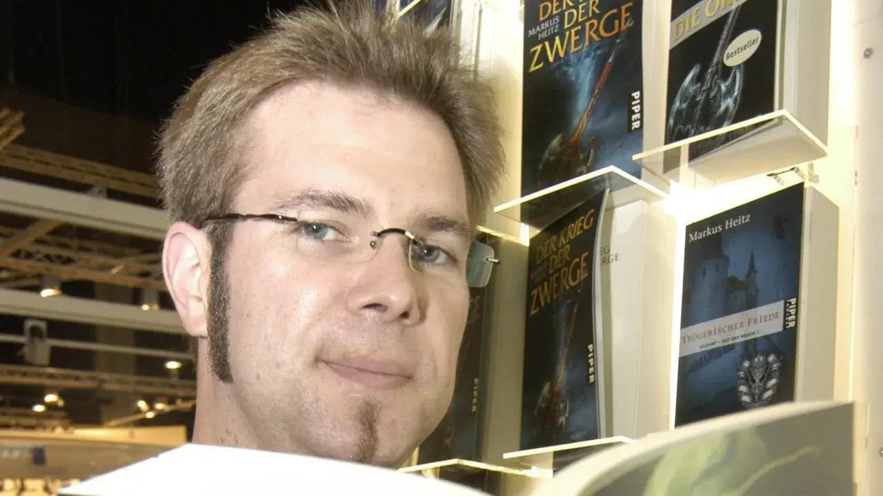 Markus Heitz, Autor von "Markus Heitz Die Zwerge Band 10", posiert vor seinen Büchern.
