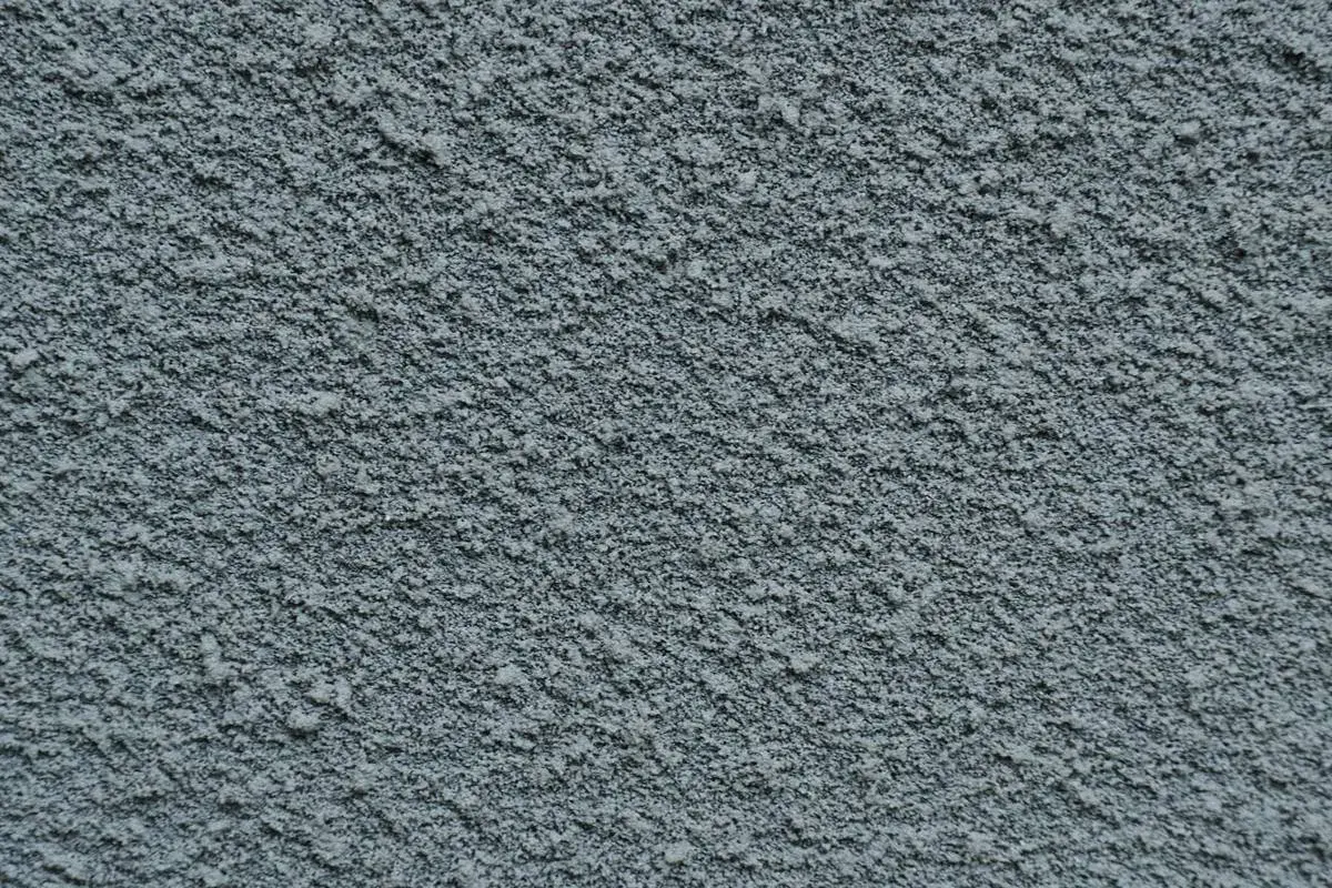 Dettaglio di pittura sabbiata grigia, con texture granulosa. Valutare i pro e contro di questo tipo di finitura per esterni.