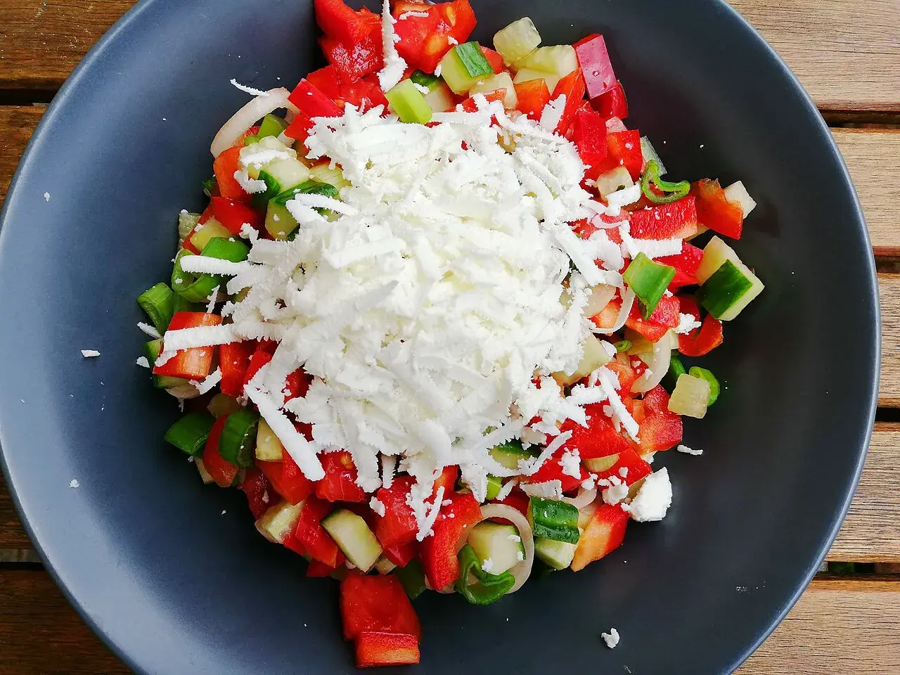 En fräsch sopska salata med hackad tomat, gurka, paprika och lök, toppad med smulad fetaost.