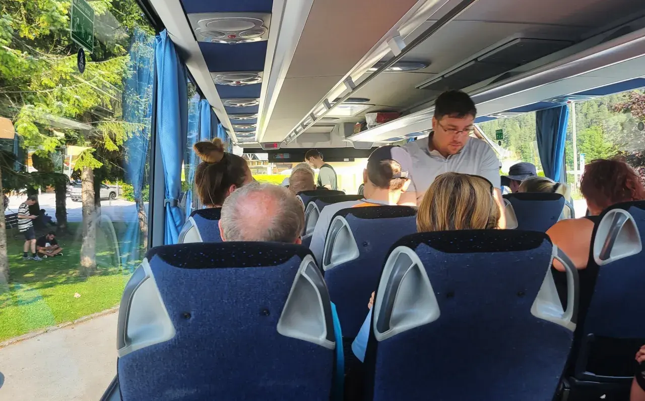 Pasażerowie w wygodnym autokarze do Londynu podziwiają zielone krajobrazy za oknem.