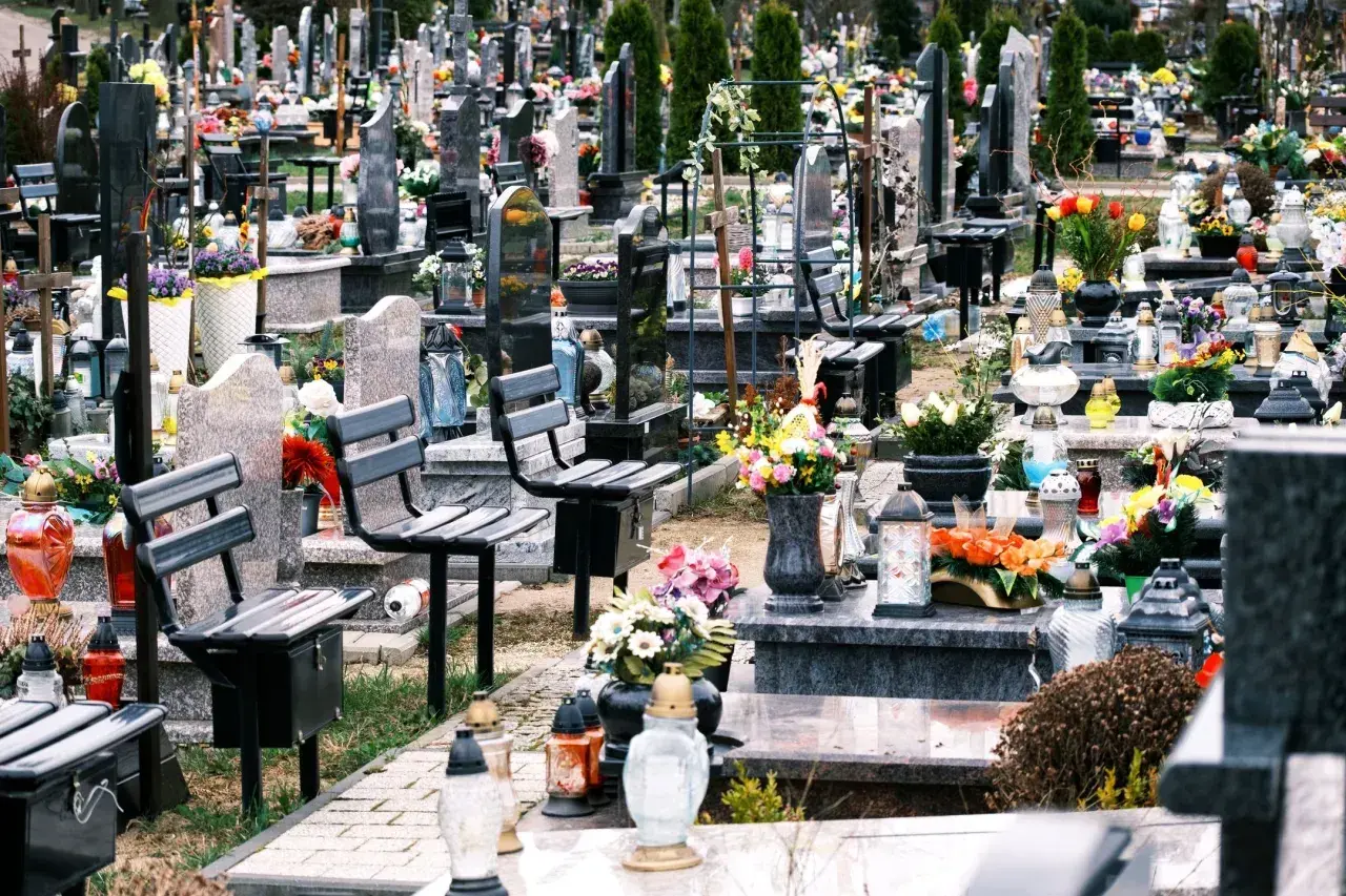 Ławki na cmentarzu, przygotowane na wizytę bliskich. Wiele zniczy i kwiatów świadczy o pamięci.
