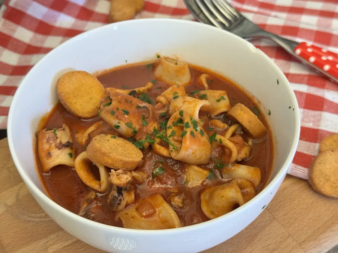 Un invitante piatto di moscardini in umido, ricchi di sapore e guarniti con prezzemolo fresco, accompagnati da crostini dorati.