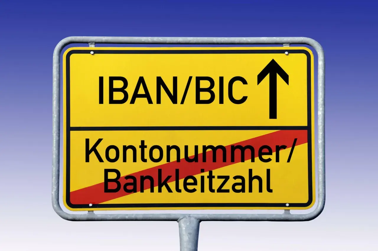 Gelbes Ortsschild mit "IBAN/BIC" und Pfeil nach oben. Darunter "Kontonummer/Bankleitzahl" durchgestrichen.
