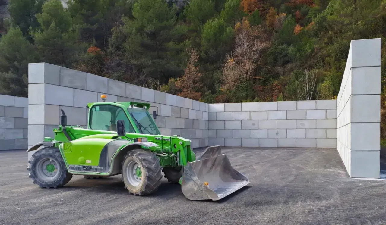 Chargeuse verte dans un espace clos de murs en blocs de béton, prêt pour le silo ensilage.