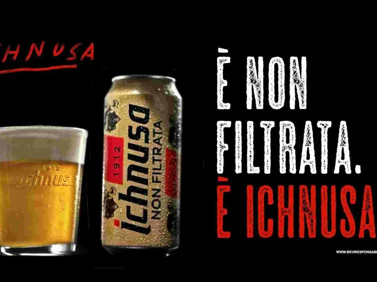 A glass of Ichnusa beer and a can of Ichnusa Non Filtrata beer on a black background.