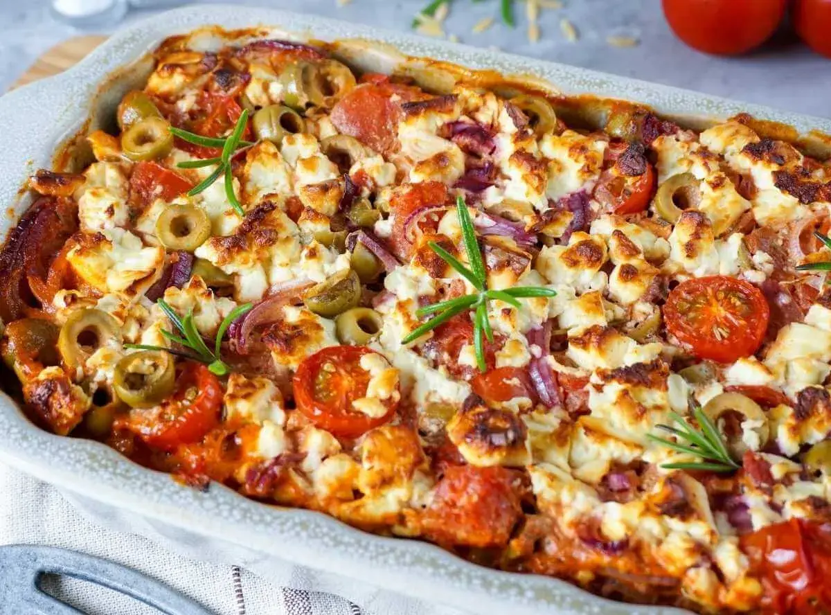 Herzhafter Kritharaki Auflauf mit Feta, Oliven, Tomaten und Rosmarin, goldbraun gebacken.